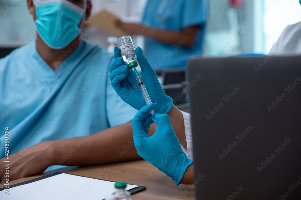 Mixed race couple of doctors wearing face masks preparing to make injection Mixed race couple of doctors wearing face masks preparing to make injection