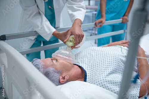 Caucasian female patient lying in hospitalbed with oxygen face mask