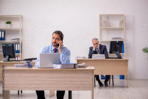 Old male boss and young employee working in the office