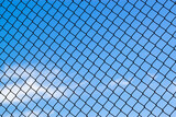 Abstract image showing a latticework of a chain fence covering the entire blue sky. Versatile for concepts like lack of freedom, humanitarian causes, captivity, slavery, limitations, restrictions