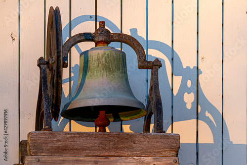 Closeup isolated image of a rusty church bell immobilized on wooden blocks through metal framing. There is an ancient wheel mechanism to operate it synchronously with other bells photo