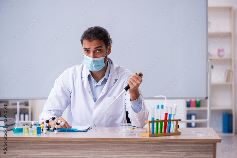Young male chemist teacher sitting in the classroom
