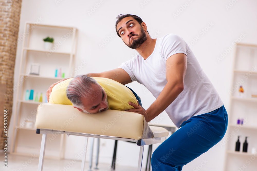 Old male patient visiting young male doctor chiropractor