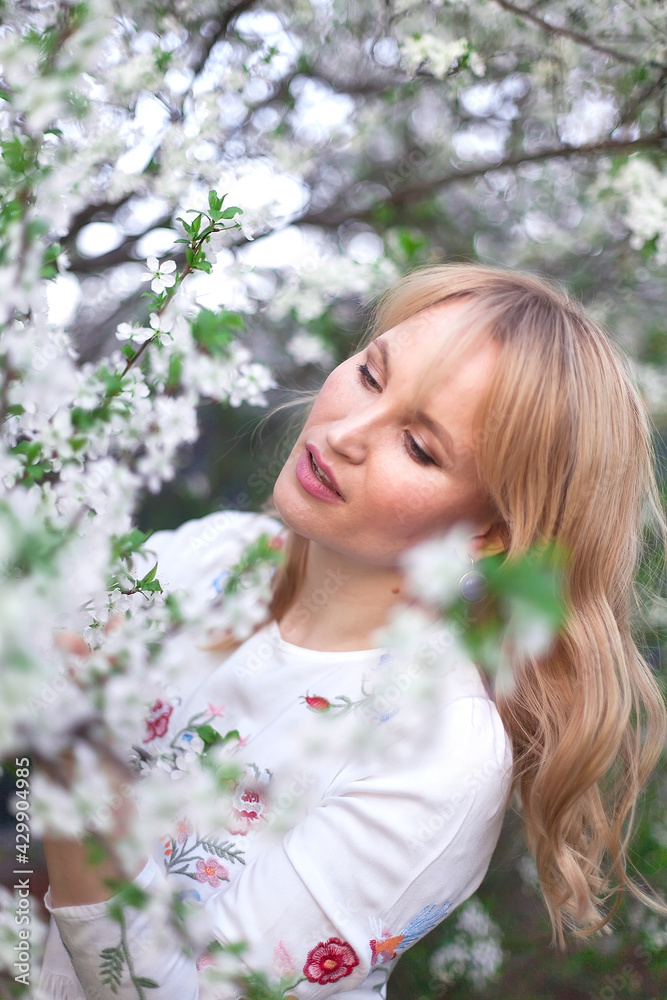 Young brunette woman posing in blooming white apple flowers on branches Young brunette woman posing in blooming white apple flowers on branches