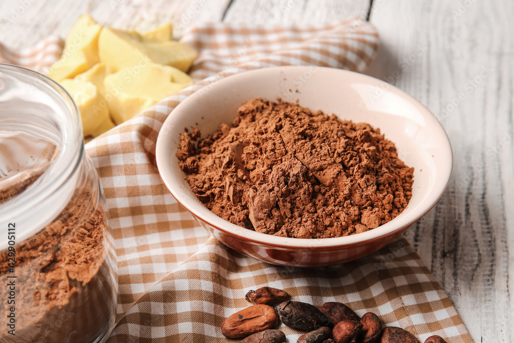 Bowl with cocoa powder on light wooden background Bowl with cocoa powder on light wooden background