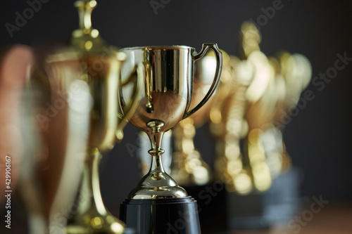 selective focus row of trophy on the wooden table against dark gray background