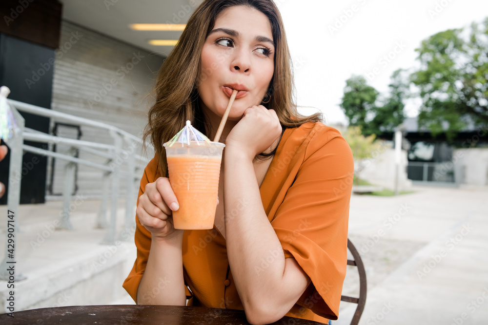 Woman drinking fresh fruit juice outdoors.