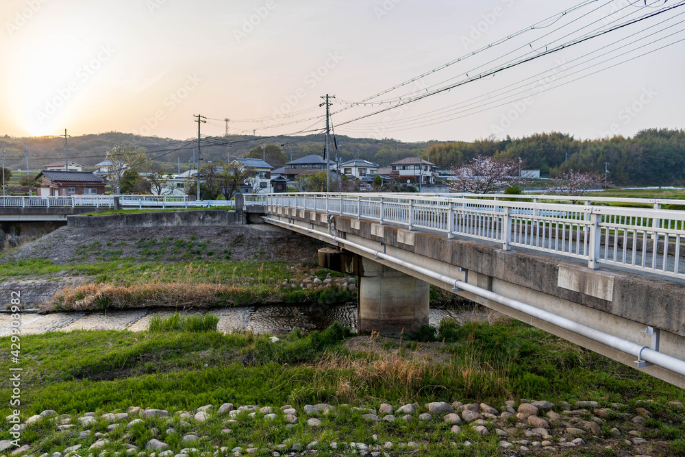 Empty bridge over quiet stream in rural japanese neighborhood at sunset