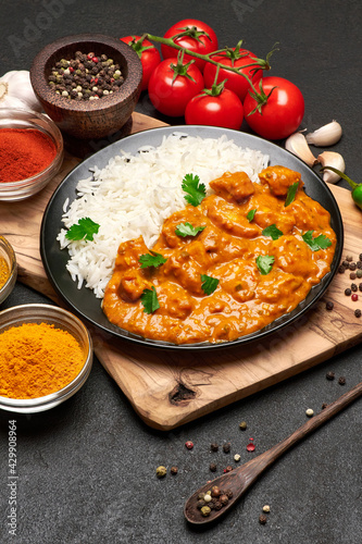 Plate of Traditional Chicken Curry, rice and spices on dark concrete background