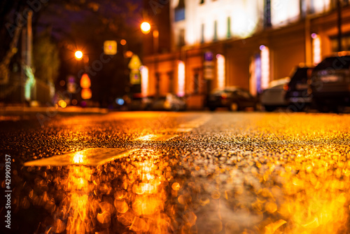 Autumn rainy night in the city. Parked cars. Residential buildings in the city center. Colorful colors. Close up view from the asphalt level.