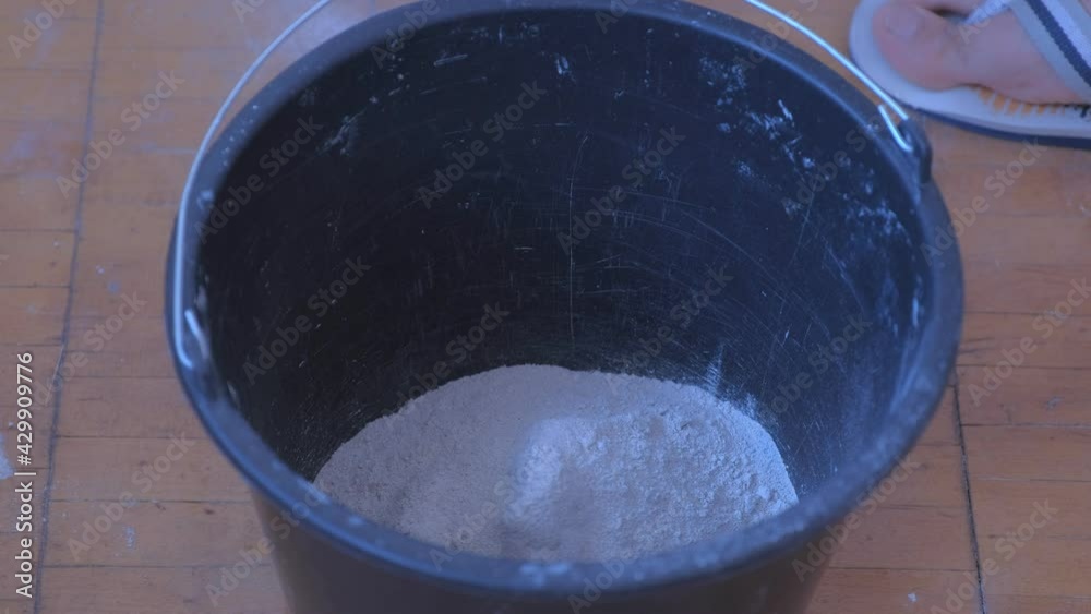 Builder is applying dry plaster and water, mixing it in bucket using an electric mixer, closeup view. Concept of construction renovation works. Preparation of mortar for plaster to alignment of wall. Builder is applying dry plaster and water, mixing it in bucket using an electric mixer, closeup view. Concept of construction renovation works. Preparation of mortar for plaster to alignment of wall.