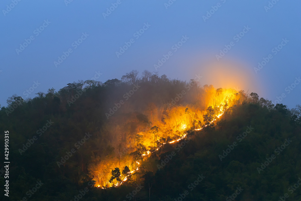 Forest fire on the mountain peak in the evening, blue sky in summer in Thailand.