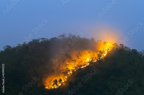 Forest fire on the mountain peak in the evening, blue sky in summer in Thailand.