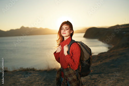 cheerful woman hiker with backpack outdoors landscape rocky mountains body of water sunset