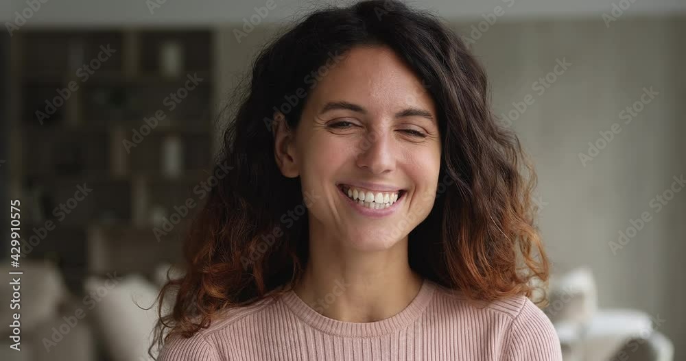 Head shot close up face view gorgeous 35s woman standing indoor smiling looking at camera. Portrait of beautiful female having wide smile with straight perfect teeth advertise dental services concept