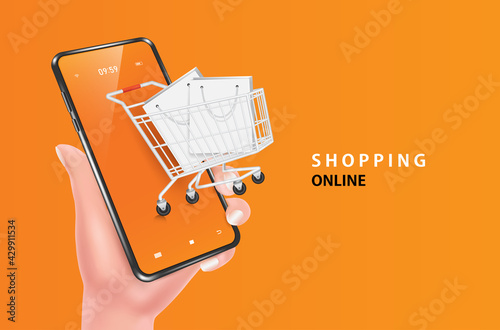 The hand was holding the smartphone and raised, with a full shopping cart and shopping bags coming out of the smartphone for shopping online concept design,object on orange background