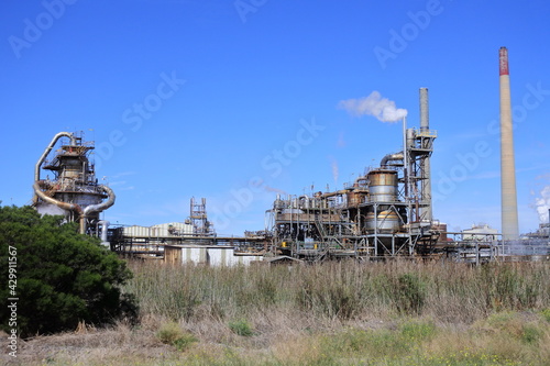 Industrial chimney with smoke against a clear blue sky