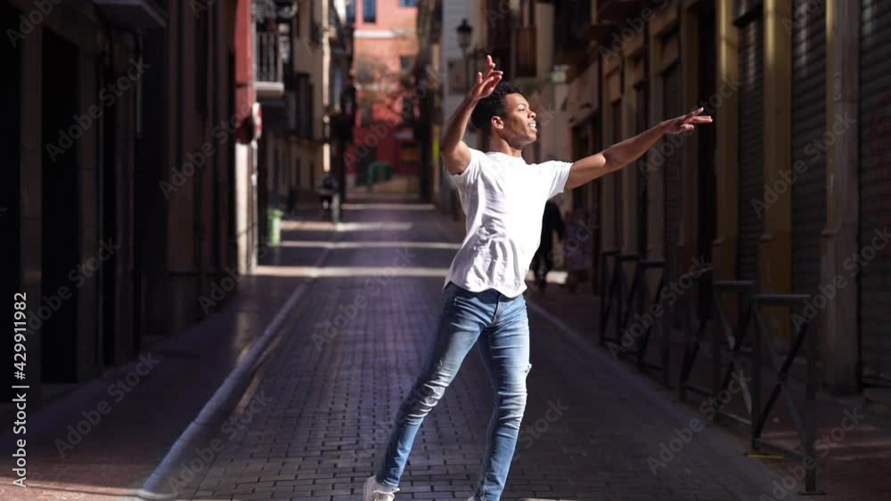 Young black male acrobat doing a ballet jump in the street. Young black male acrobat doing a ballet jump in the street.