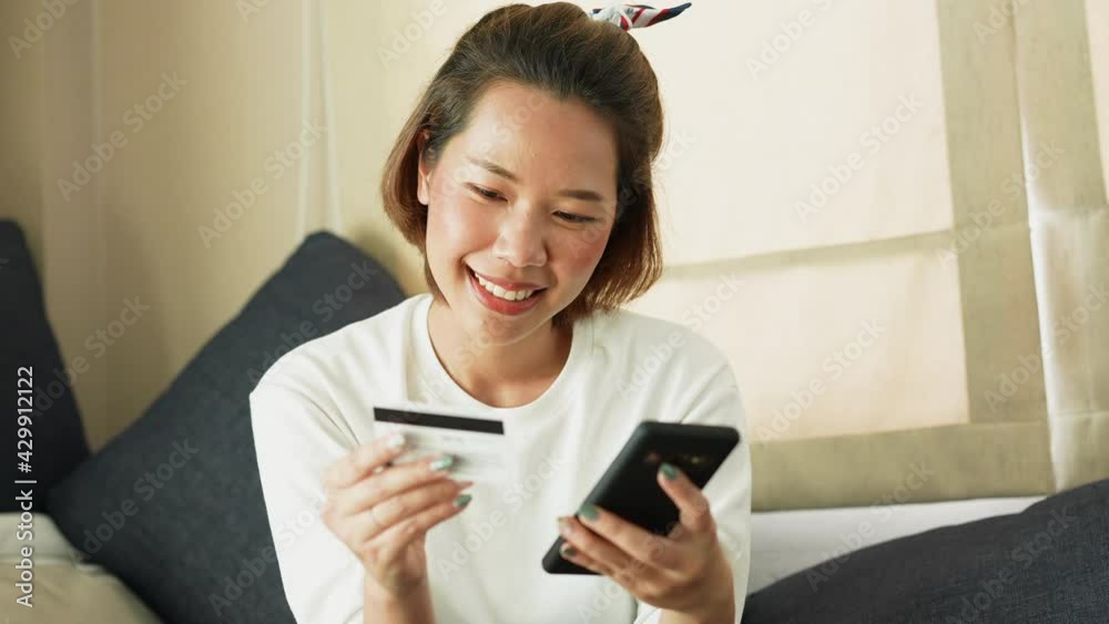 slow motion scene on asian woman using smartphone device to search items or things on online shopping website store and payment by credit card in living room , lifestyle people concept slow motion scene on asian woman using smartphone device to search items or things on online shopping website store and payment by credit card in living room , lifestyle people concept