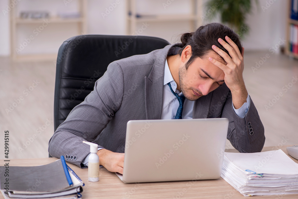 Young male employee unhappy with excessive work in the office Young male employee unhappy with excessive work in the office