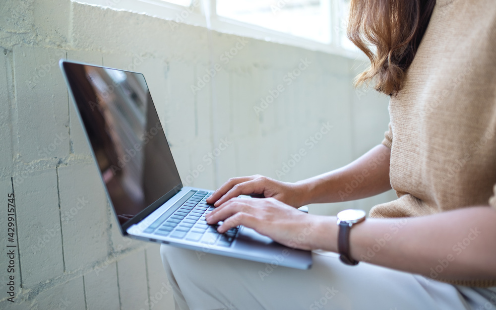 Fototapeta premium Closeup image of a woman working and typing on laptop computer keyboard