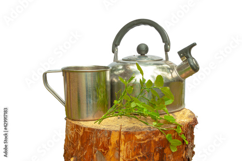 A camping kettle with a mug stands on a wooden stump. All on a white background.