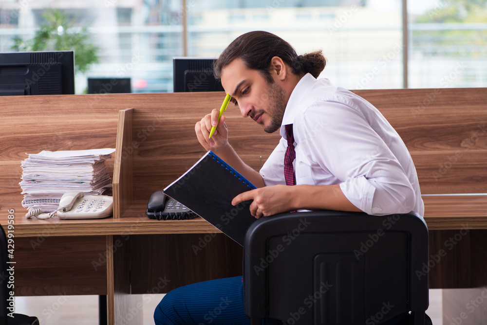 Young male employee and too many work in the office Young male employee and too many work in the office