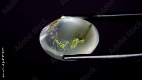 natural moss quartz gemstone in tweezer on the turning table photo