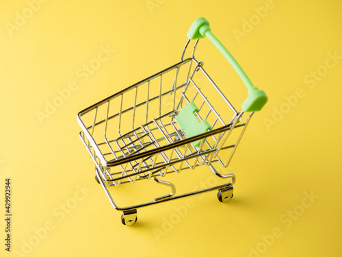 Close-up of green shopping carts on a yellow background. Sales concept. Cart, products.