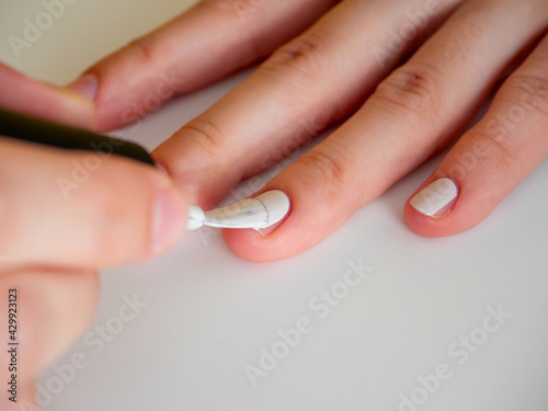 applying white nail polish to the nail. Manicure and nail care concept