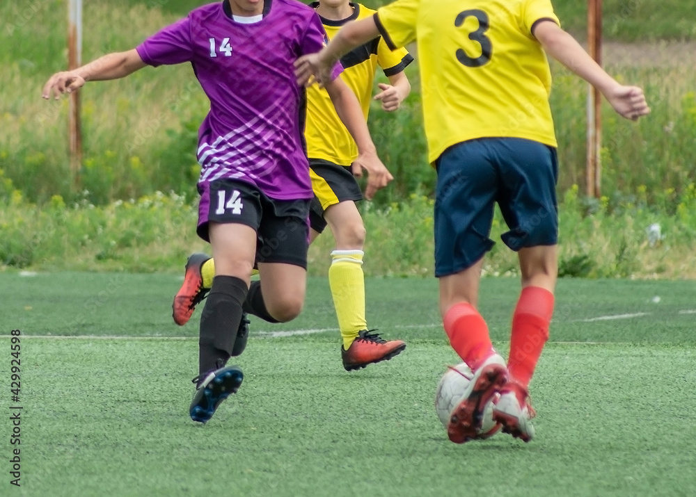 Obraz premium Children's football. An interesting football moment at the match and training. The active struggle and dynamics of the boys' soccer match. The boys are recklessly fighting for the ball