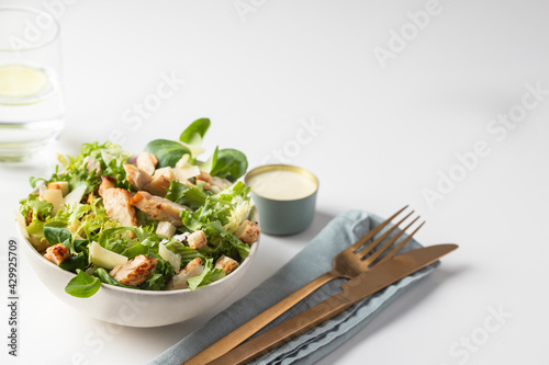 Cesar salad plate served with water glass, sauce bowl and cutlery in restaurant table. photo