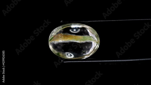 natural moss quartz gemstone in tweezer on the turning table photo