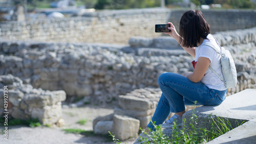 Girl - tourist takes photos of the ancient city on the phone