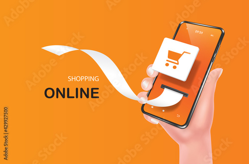The hand is holding the smartphone up and there is a shopping cart icon on the screen. And a receipt paper flowed out for shopping online concept,object on orange background