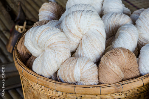 Closed up natural soft white and brown cotton thread bundle in wooden basket ready for fabric or cloth production