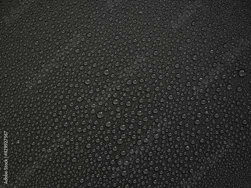 abstract horizontal background: water drops with reflections of light on a dark gray surface