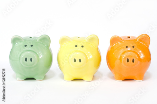 Closed up little gree, yellow, and orange piggy bank on white background, for saving and investment concept