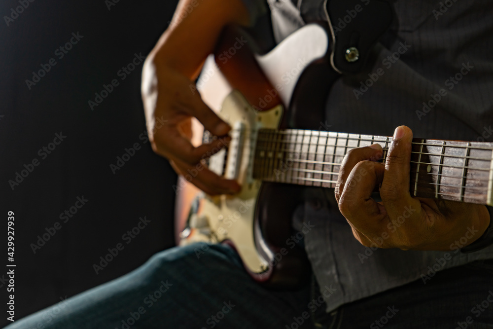 Fototapeta premium Hands of the man playing electric guitar. Low key photo.