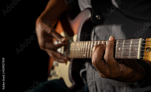 Hands of the man playing electric guitar. Low key photo.