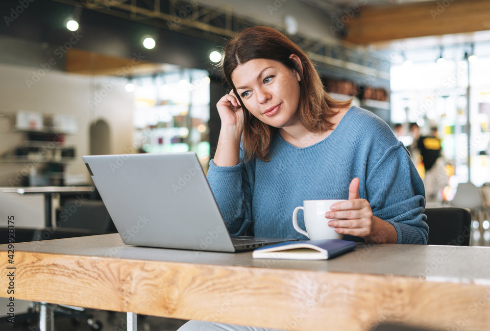 Beautiful stylish young woman plus size body positive using laptop at beauty salon office, small business owner