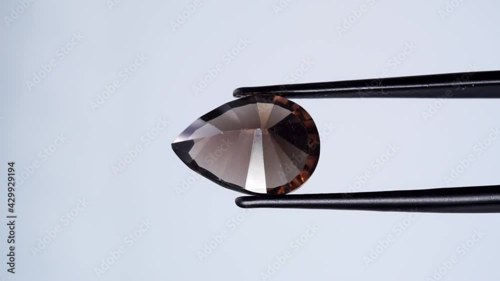natural smoky quartz gemstone in tweezer on the turning table natural smoky quartz gemstone in tweezer on the turning table