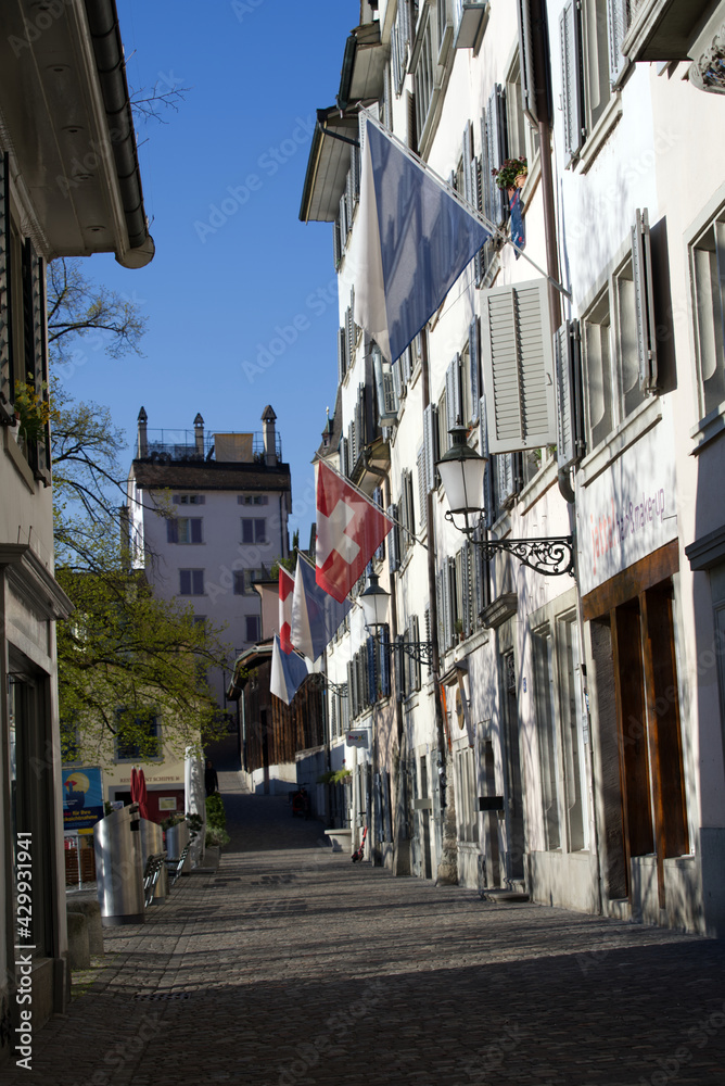 Alley at the old town of Zurich (Schipfe) with Swiss flags in the morning. Photo taken April 21st, 2021, Zurich, Switzerland.