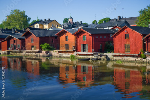 Old wooden warehouses on the banks of the Porvoonjoki river in the light of the evening sun on a summer evening. Porvoo, Finland