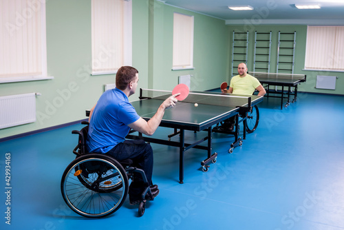 Adult disabled men in a wheelchair playing table tennis