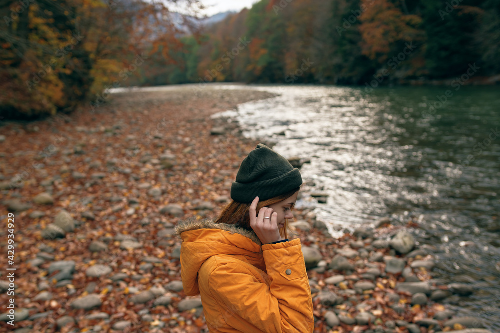 woman in autumn clothes on nature near the river walk the mountains