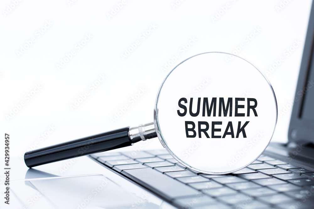 magnifier on laptop keyboard with summer break magnifier on laptop keyboard with summer break