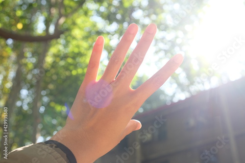 Left hand reaching sunlight against the sky 