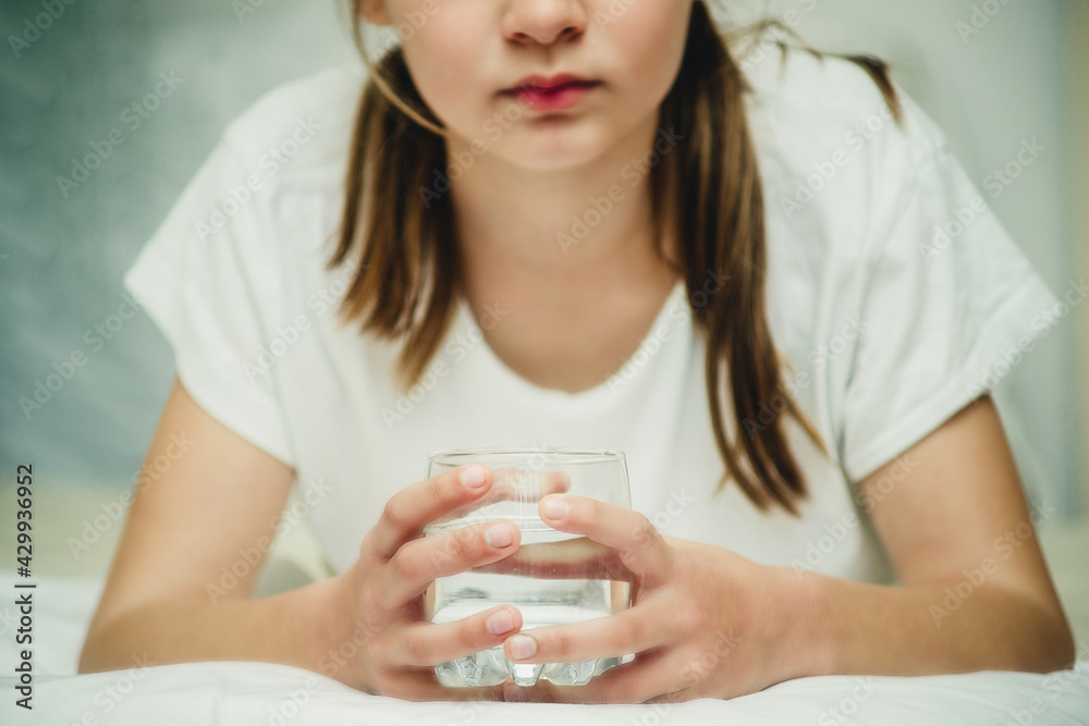 teenage girl with a glass of water on the bed close-up teenage girl with a glass of water on the bed close-up