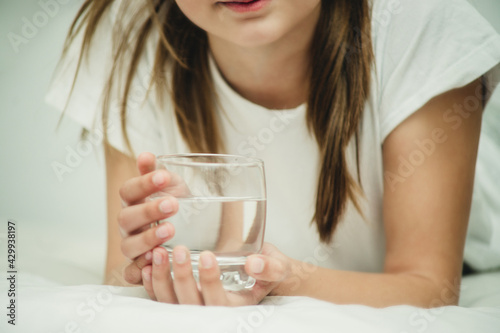 girl with a glass of water on the bed
